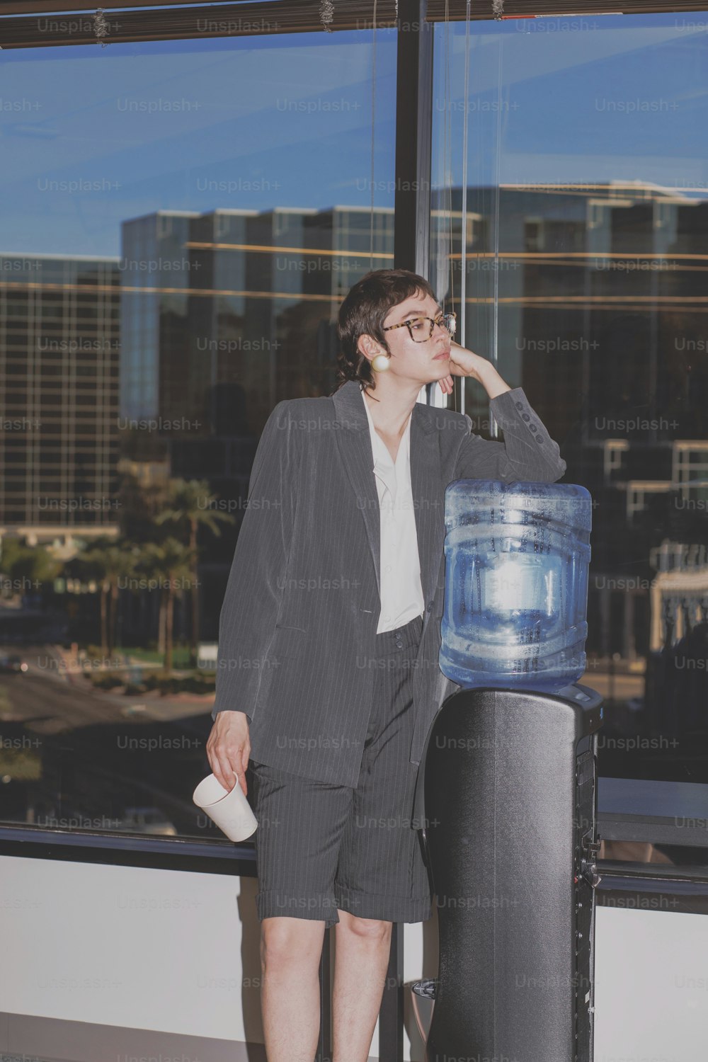 Una mujer de pie junto a un dispensador de agua frente a una ventana