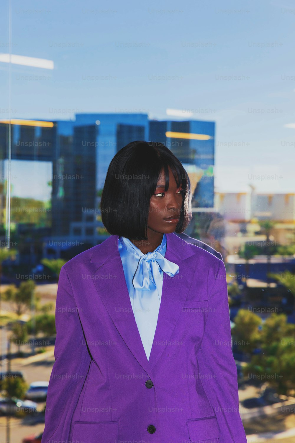 a woman in a purple suit standing in front of a window