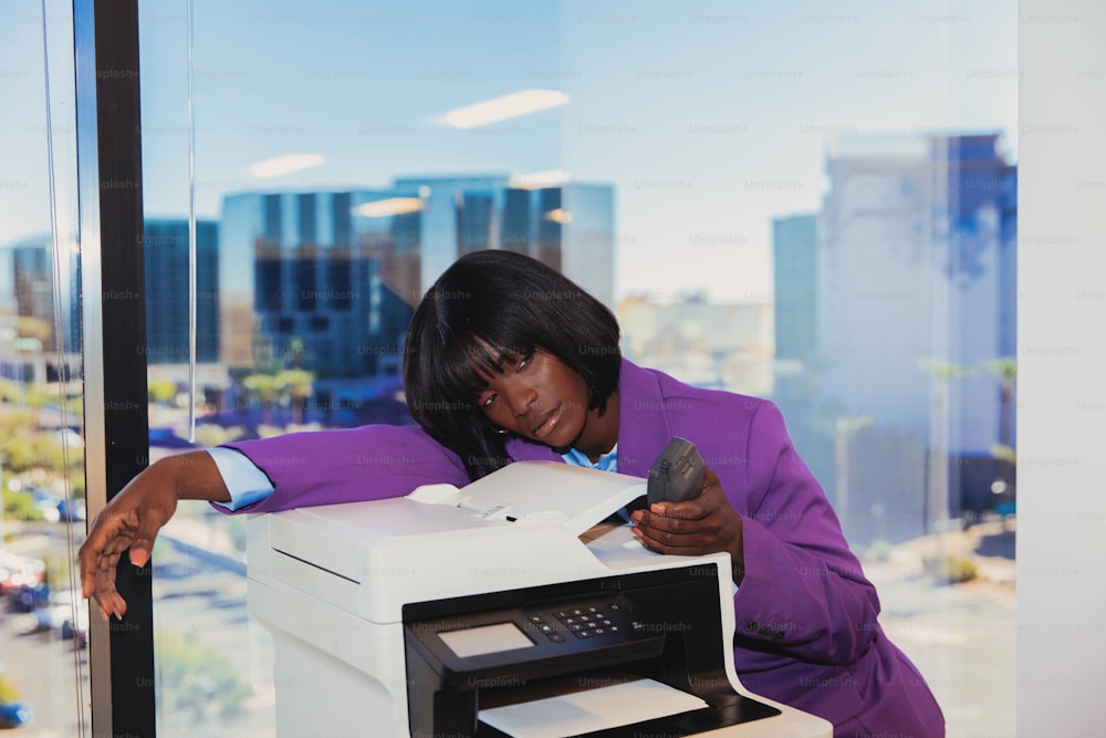 a woman in a purple jacket looking at a printer