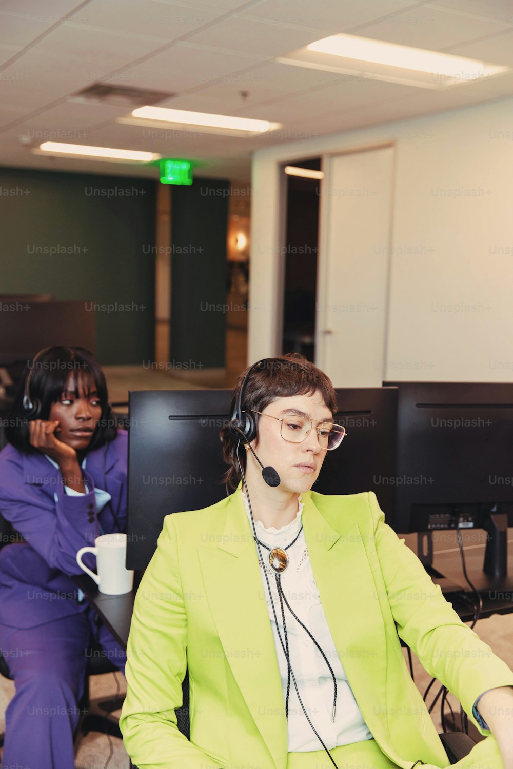 a woman sitting in front of a computer monitor wearing a headset
