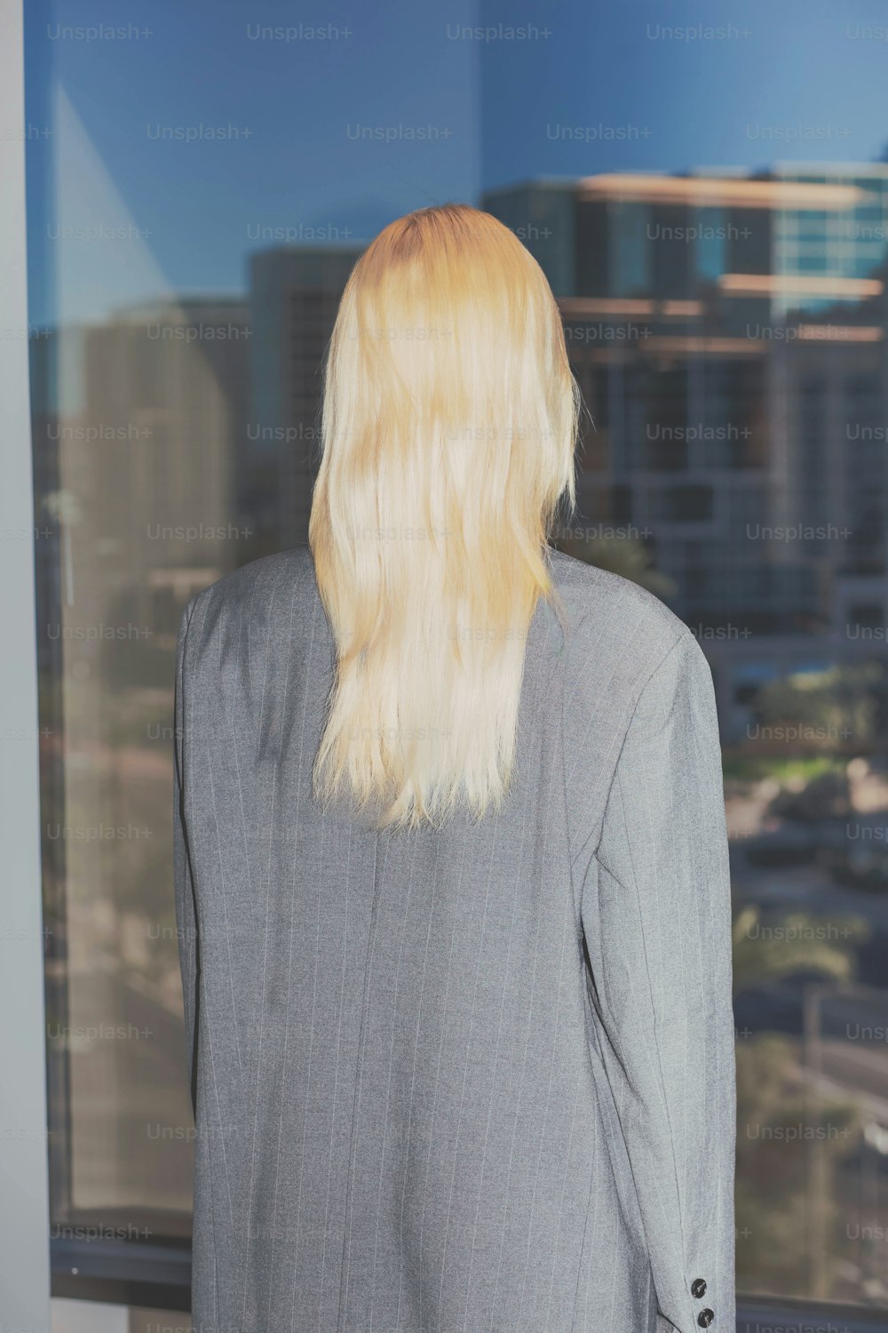 a woman with blonde hair standing in front of a window