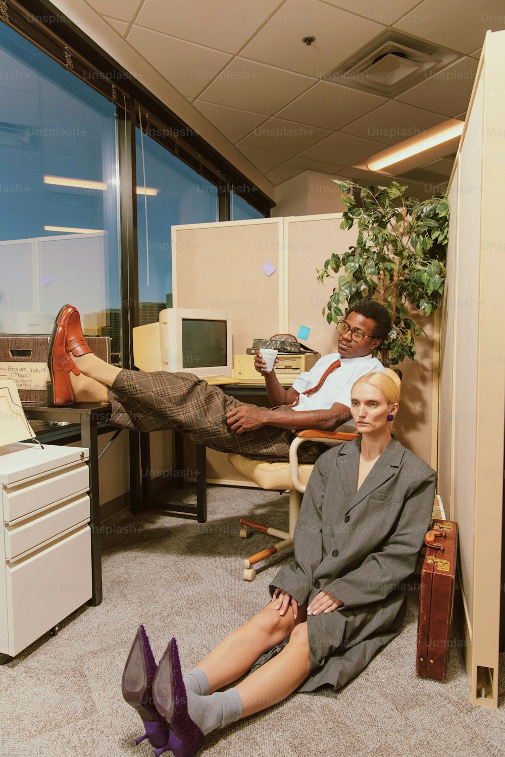 a man and woman sitting on the floor in an office