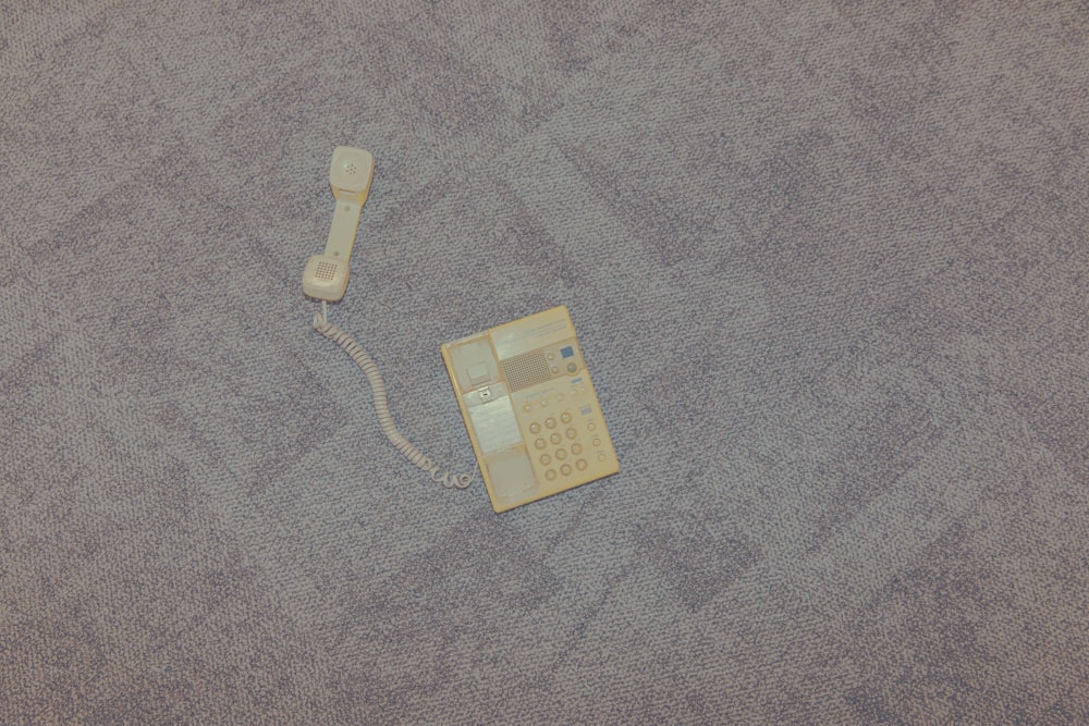 a phone laying on the ground with a cord attached to it
