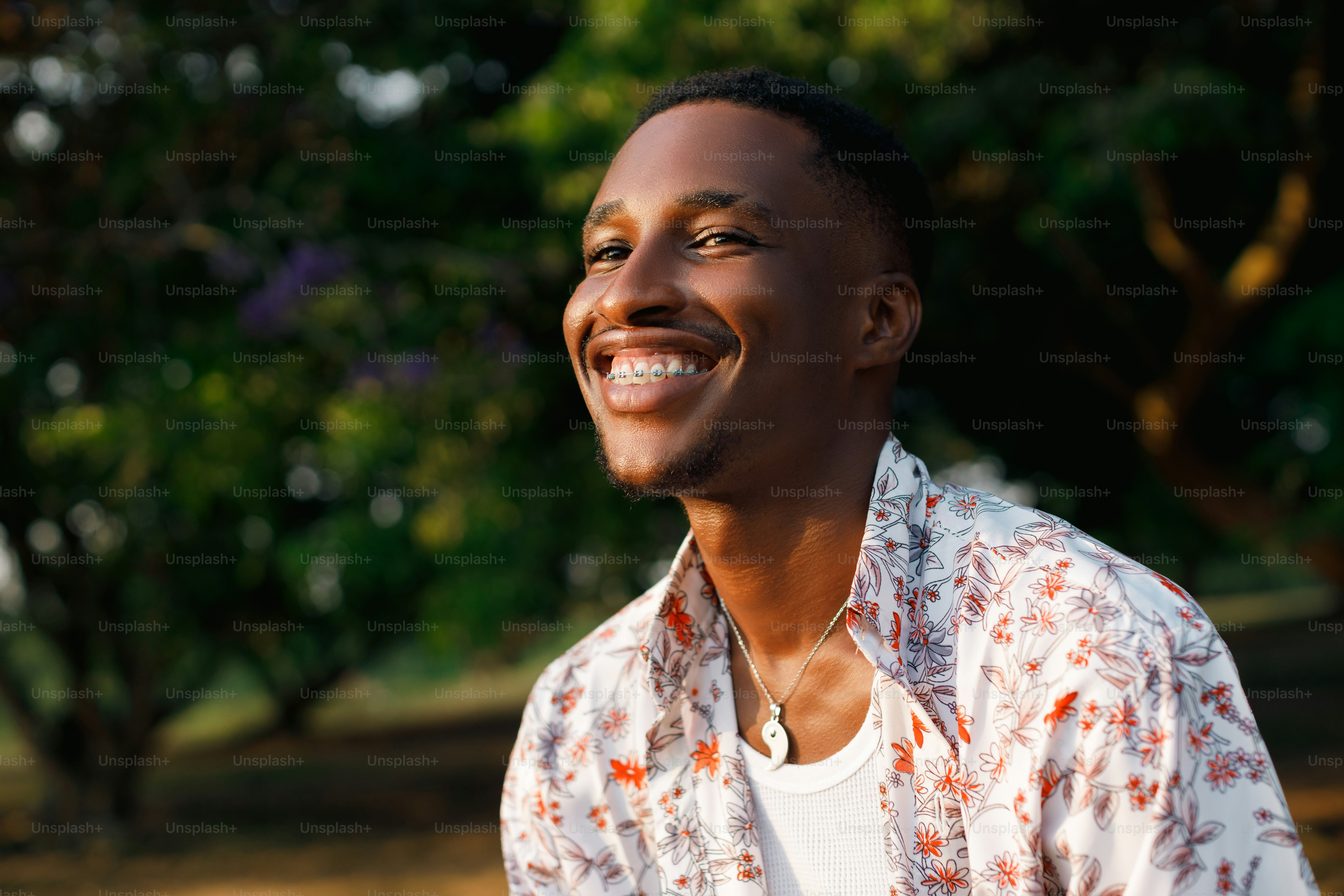 a man smiles while sitting in a park