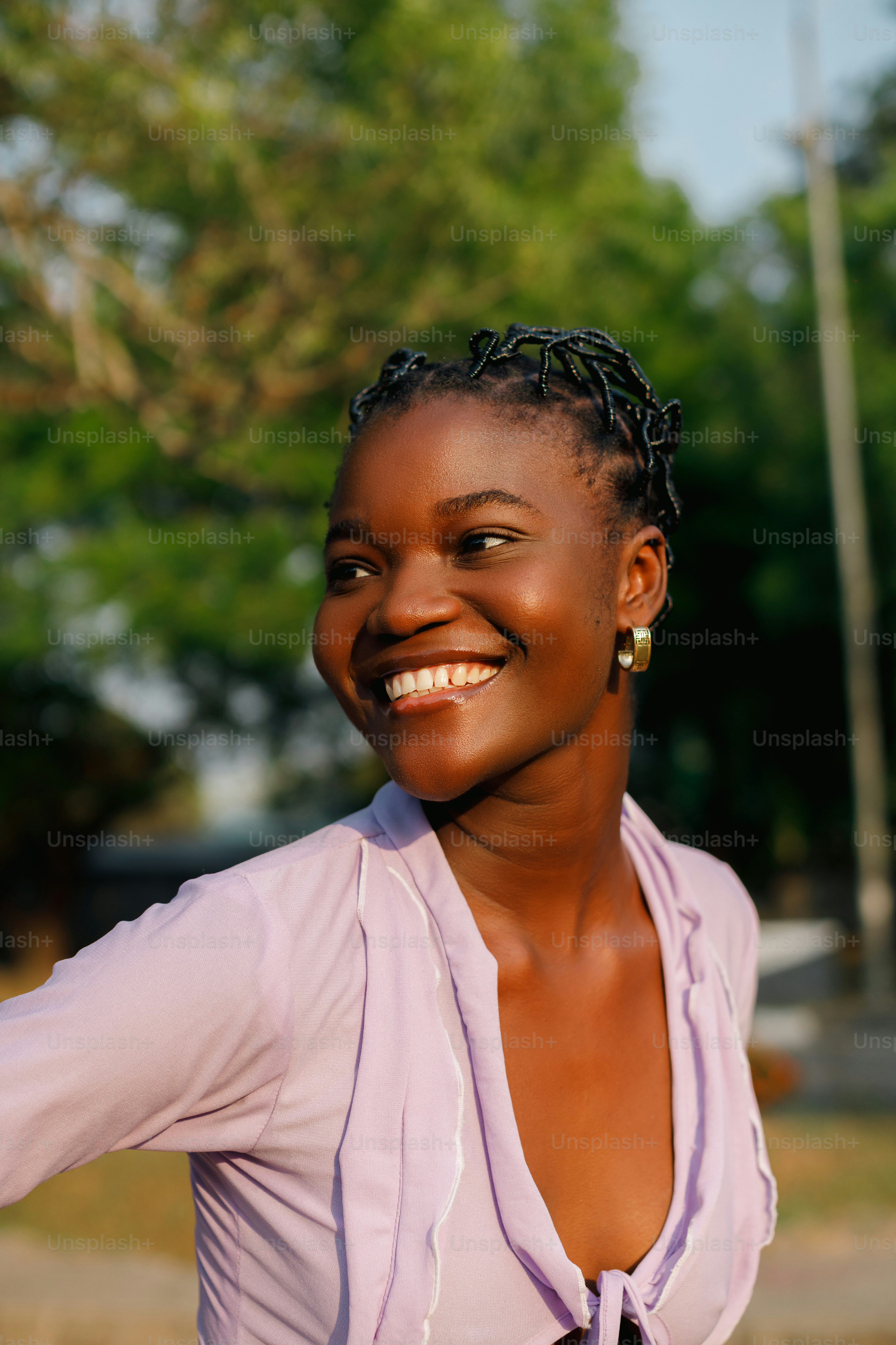 a woman with braids smiling and wearing a purple shirt