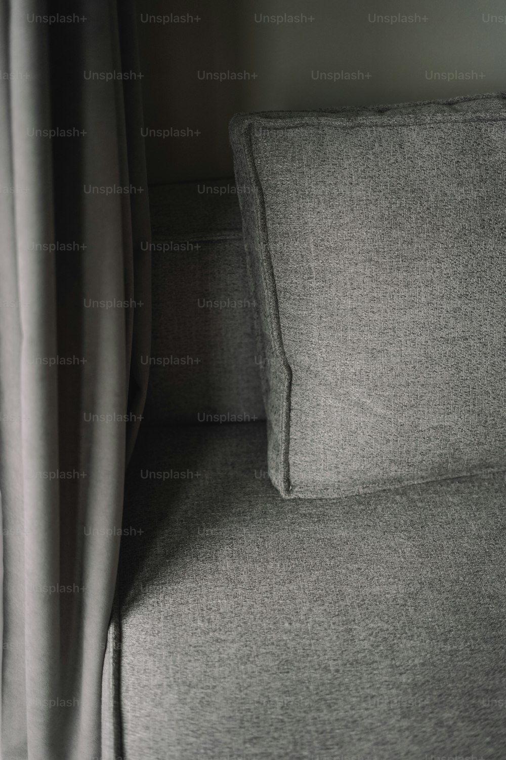 a close up of a gray couch with a curtain