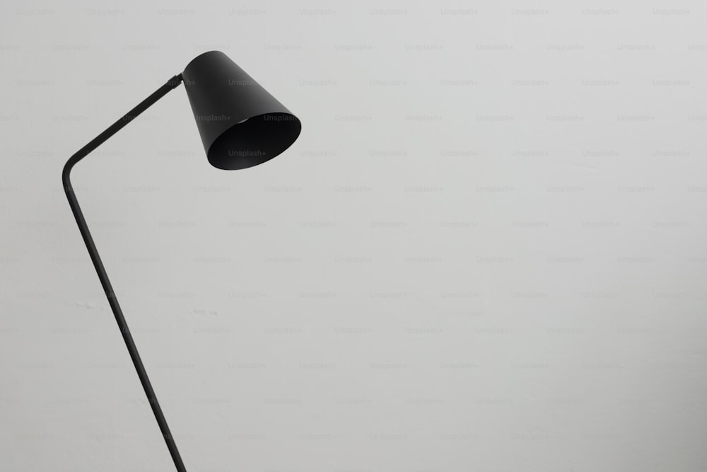 a black floor lamp on a white wall