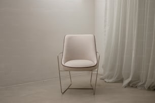 a white chair sitting in front of a curtain