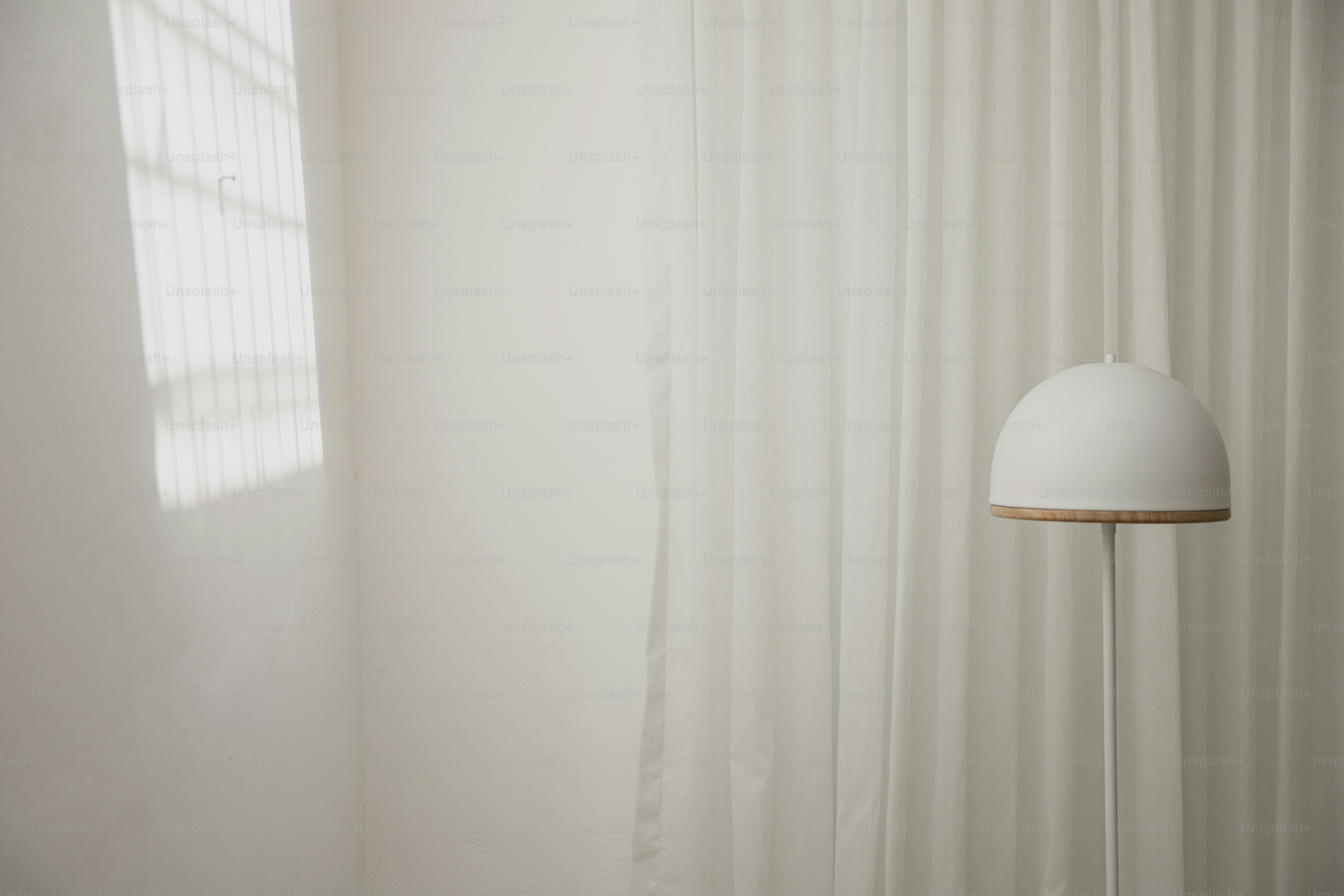 une lampe blanche posée à côté d’un rideau blanc