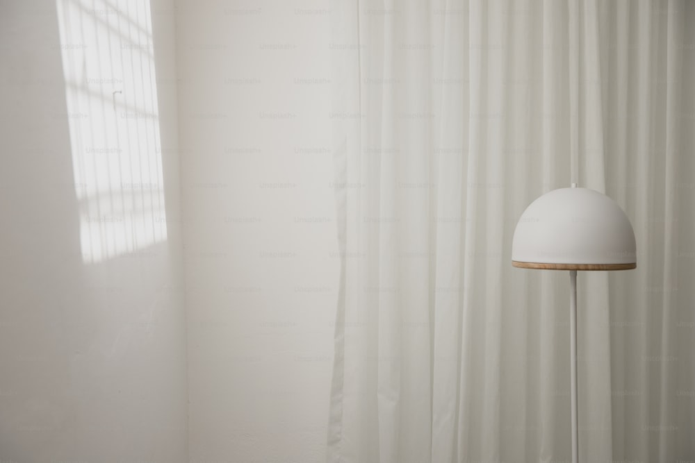 eine weiße Lampe, die neben einem weißen Vorhang sitzt