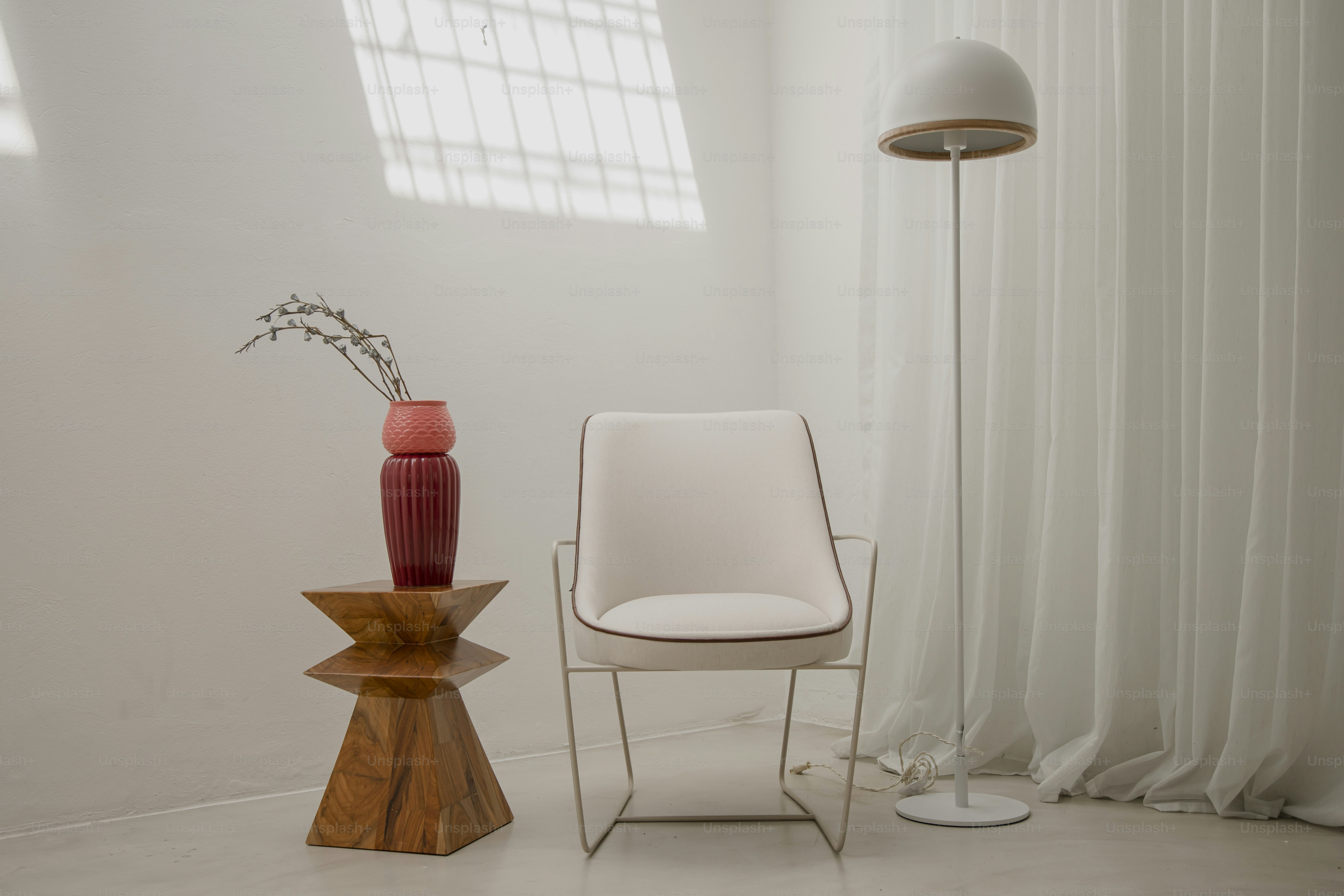 une chaise blanche et un vase rouge dans une pièce