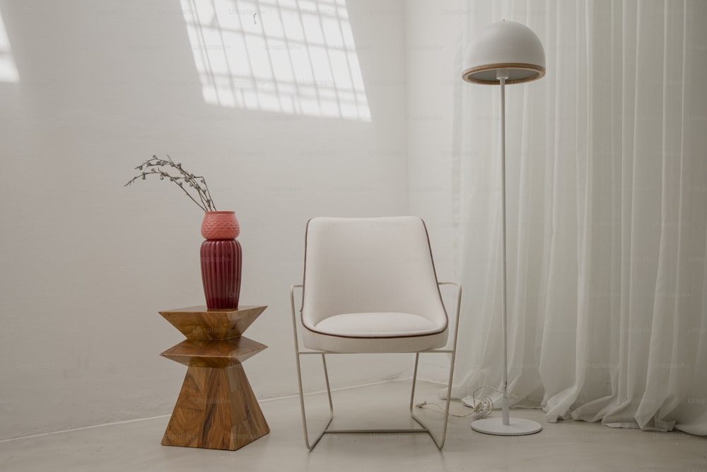 a white chair and a red vase in a room