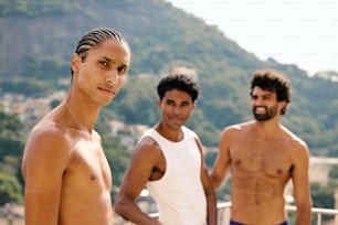 three men standing next to each other in front of a mountain