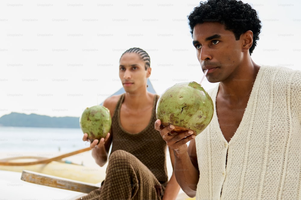 해변에 앉아 코코넛을 들고 있는 남자와 여자
