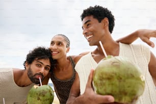 two men and a woman are holding coconuts