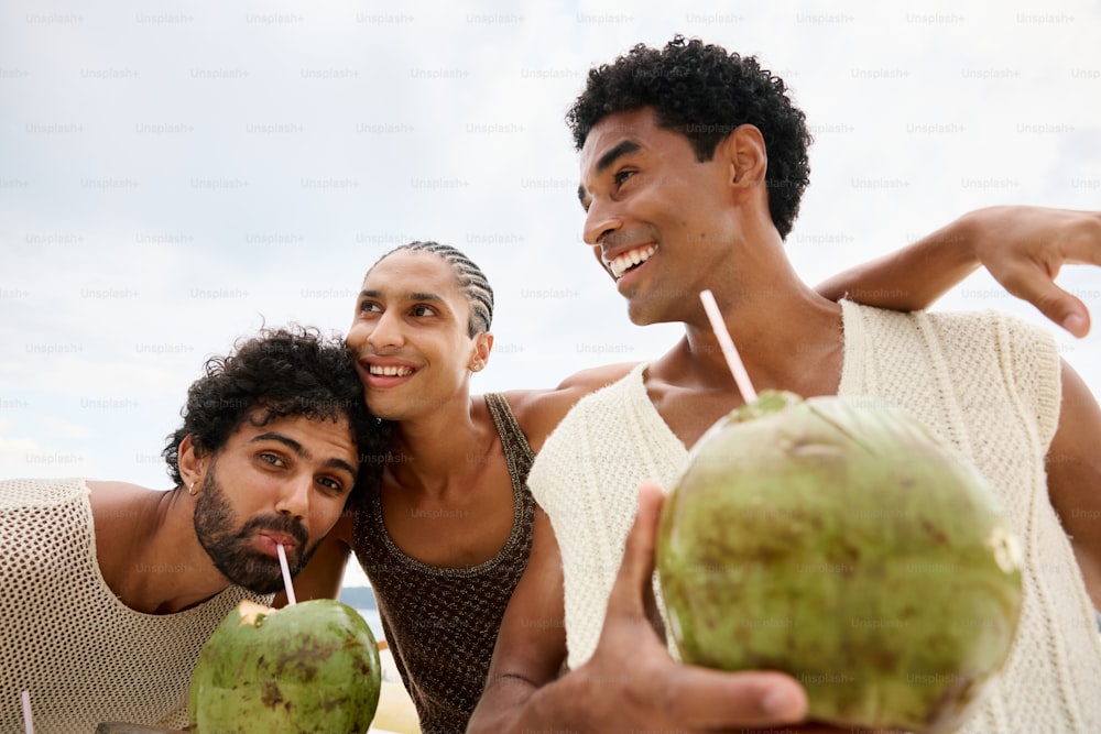 two men and a woman are holding coconuts