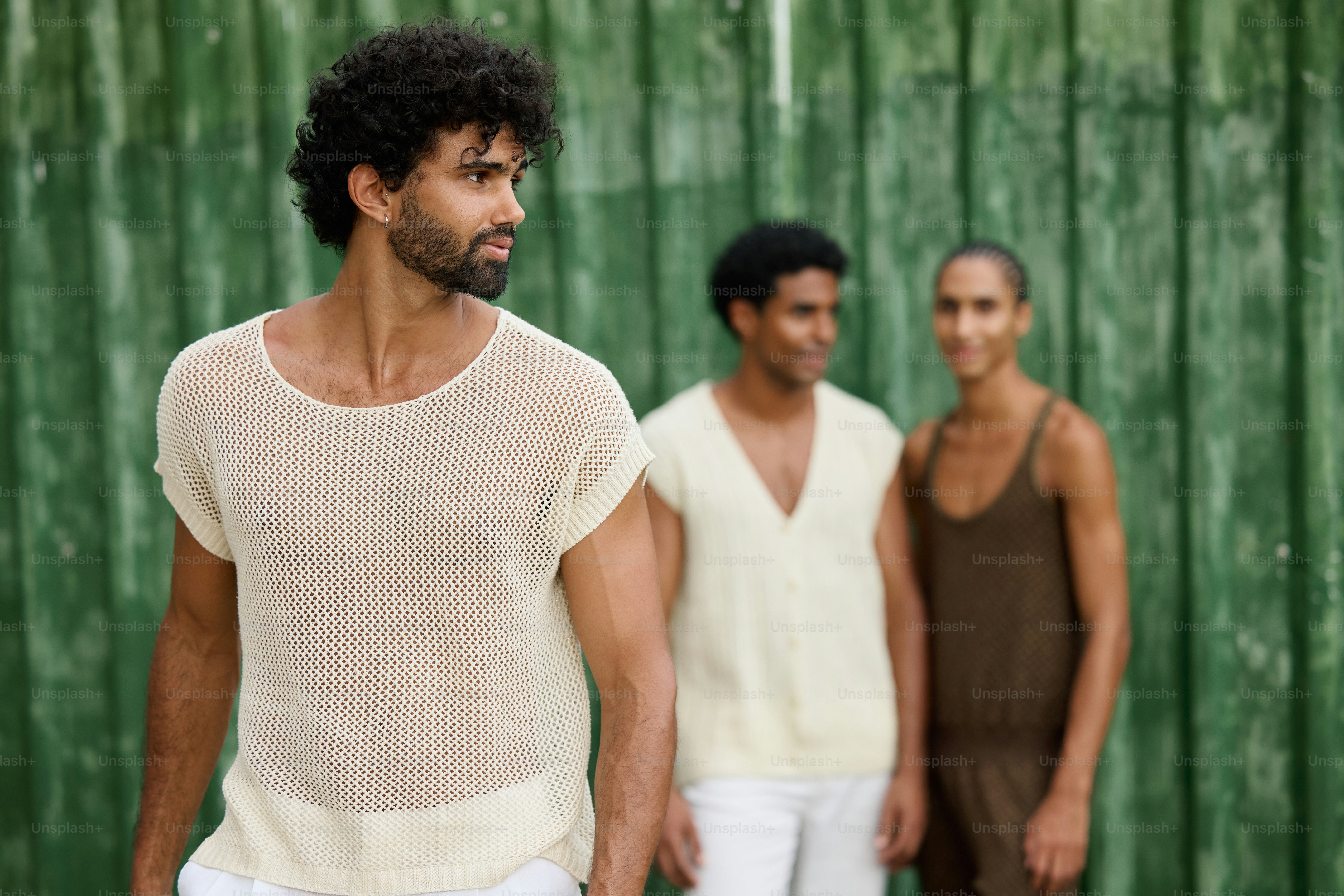 two men standing next to each other in front of a green wall