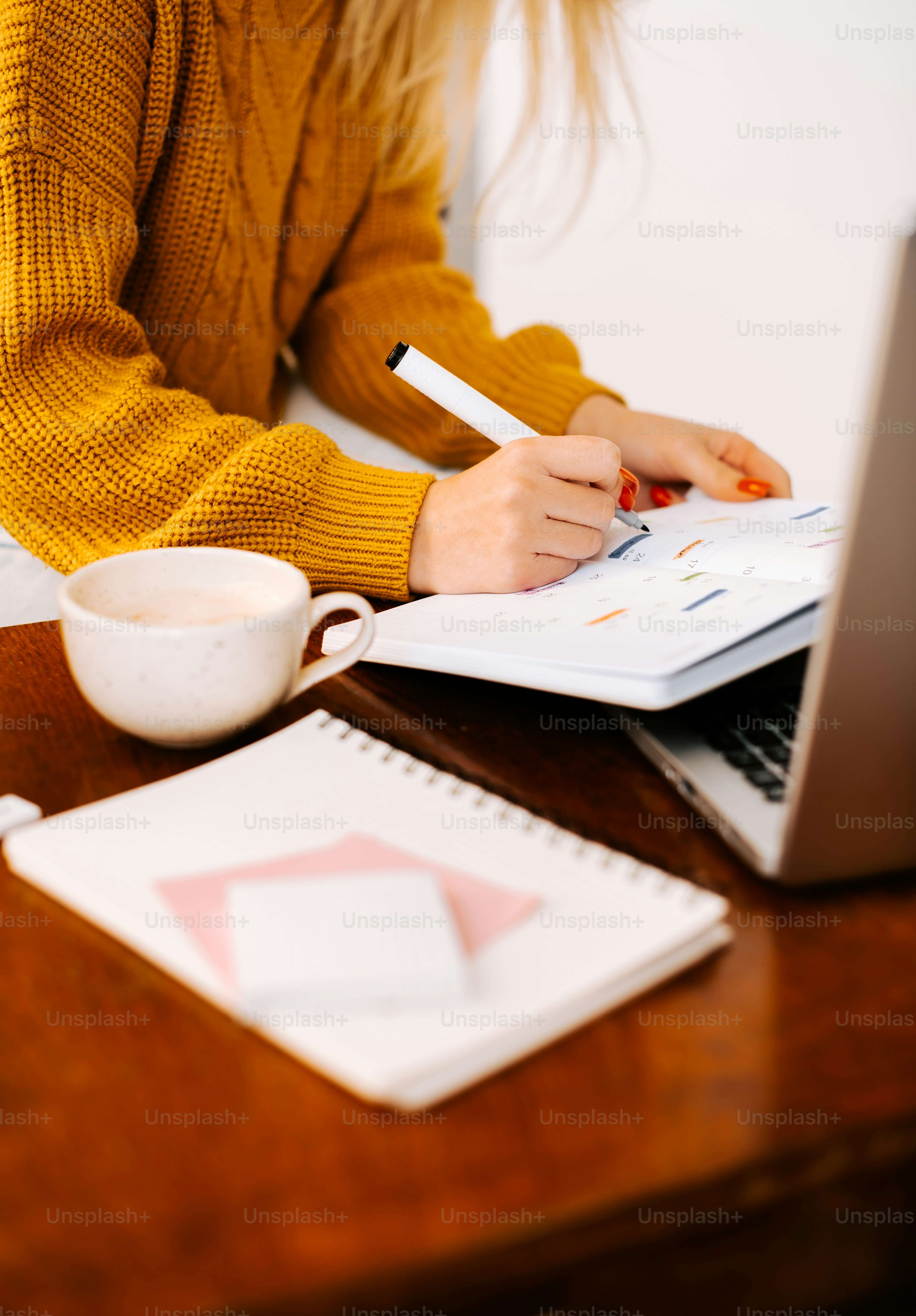 a woman sitting at a desk writing on a notebook