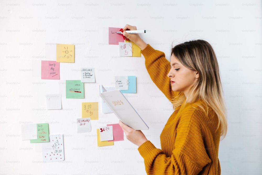 a woman writing on a wall with sticky notes on it