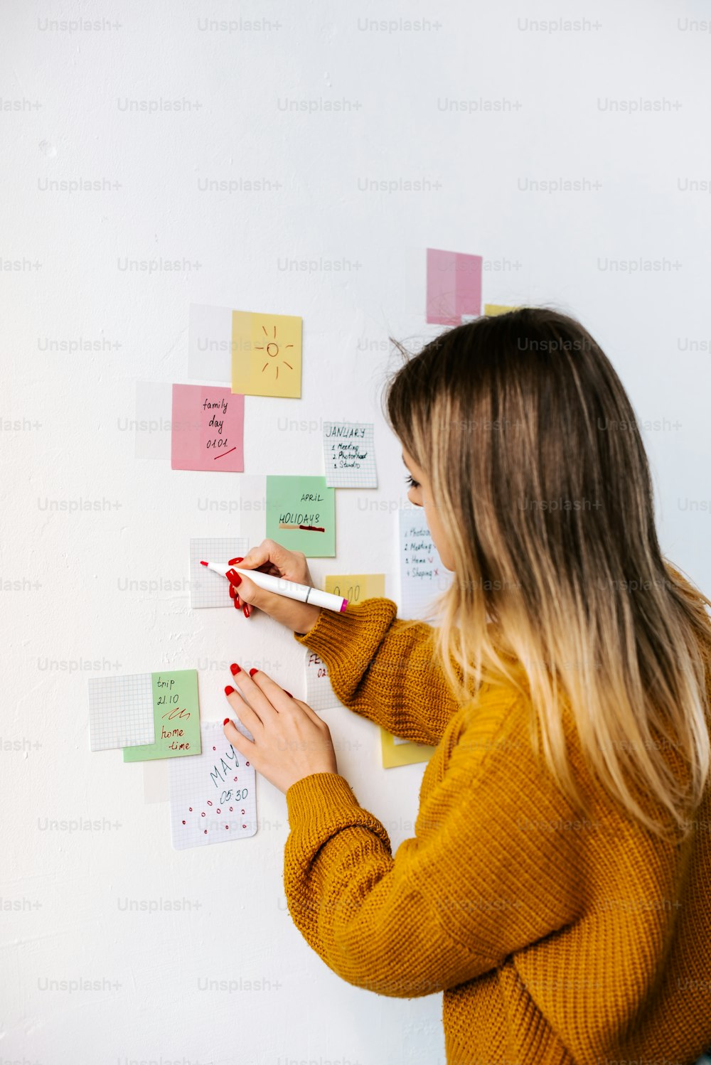 a woman writing on a wall with sticky notes