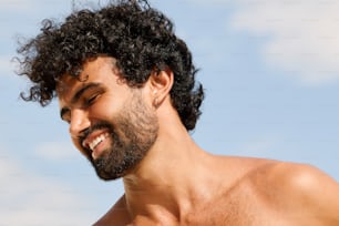 un hombre con cabello rizado y barba sonriendo