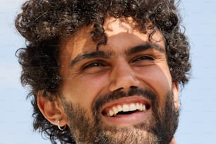 a close up of a man with curly hair smiling