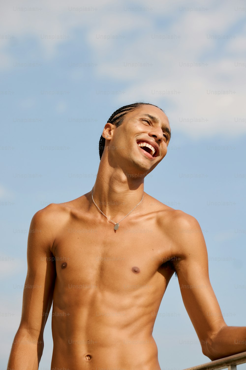 a man without a shirt standing next to a fence