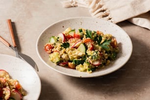 a white bowl filled with food next to a plate of vegetables