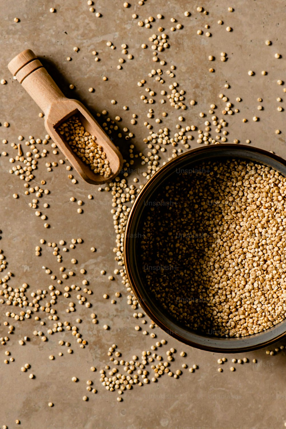 a bowl of grain next to a wooden scoop