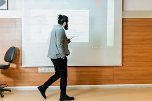 a man in a business suit walking past a projector screen