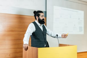 a man standing at a podium in front of a projector screen