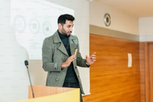 a man standing at a podium in front of a projector screen