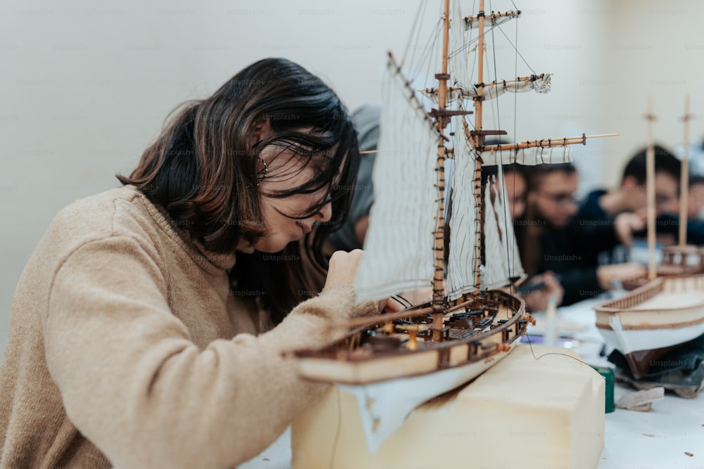 a woman working on a model of a ship