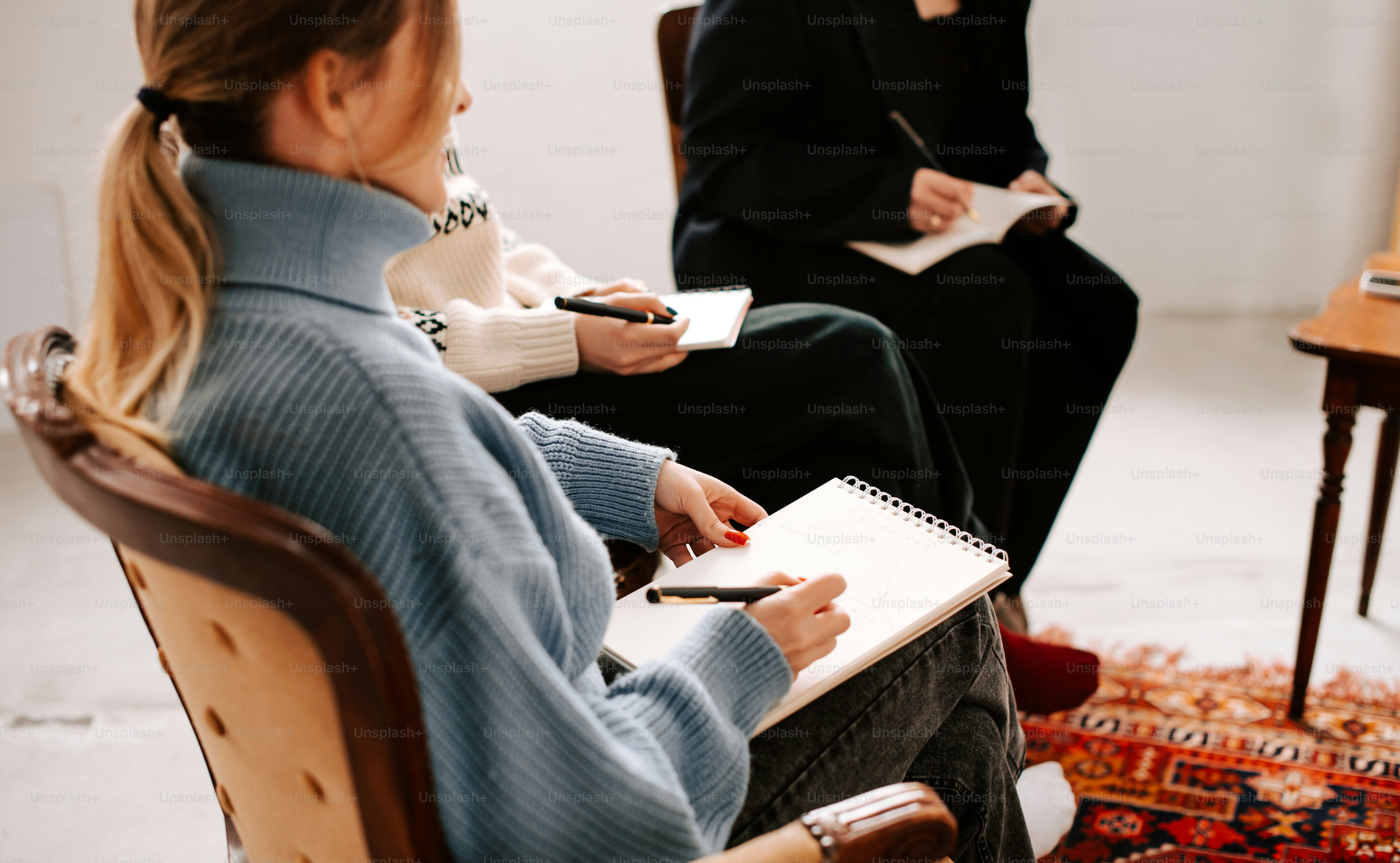 two women sitting in chairs with notebooks in their hands