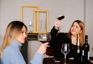 two women sitting at a table with wine glasses