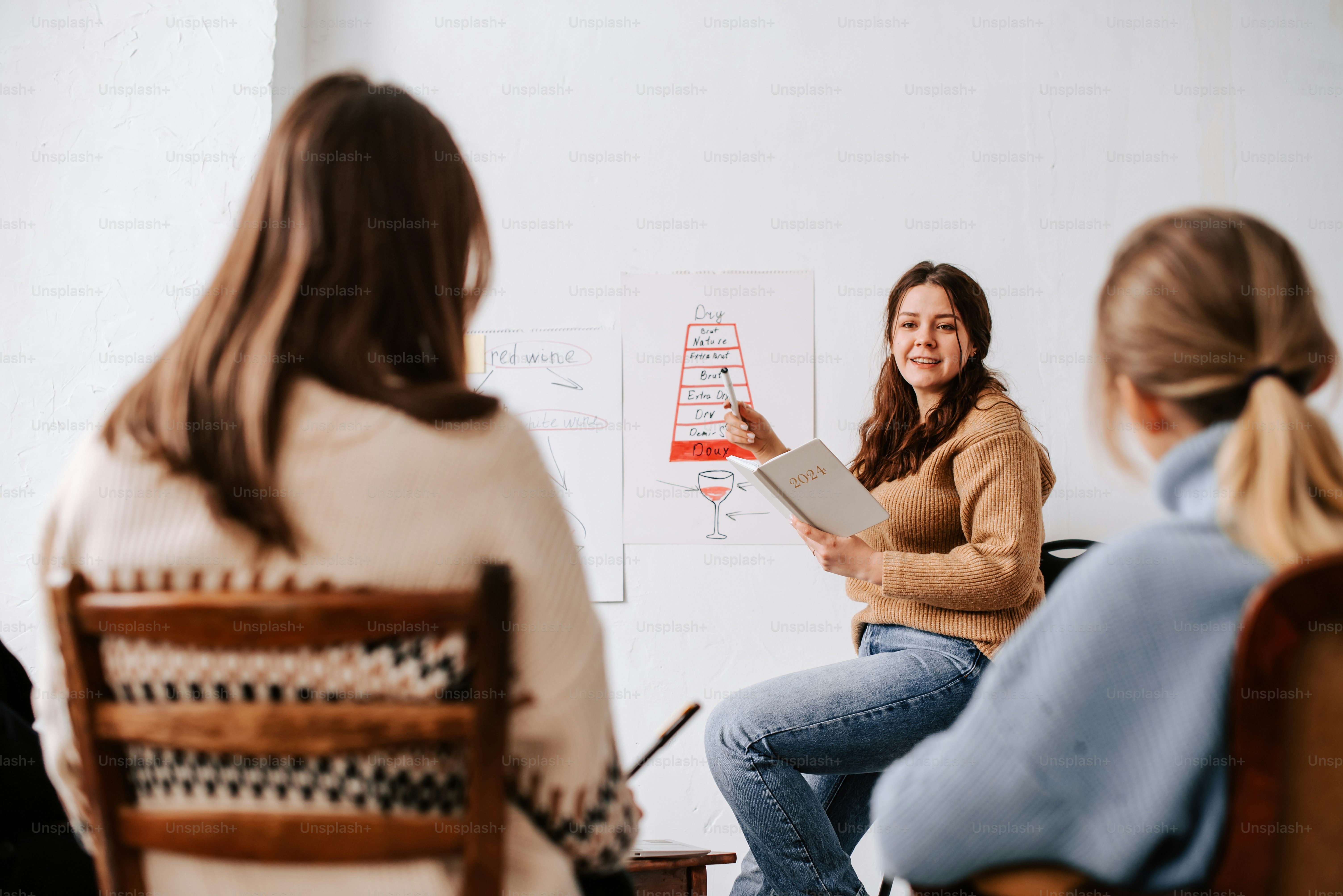 a woman sitting on a chair in front of a whiteboard