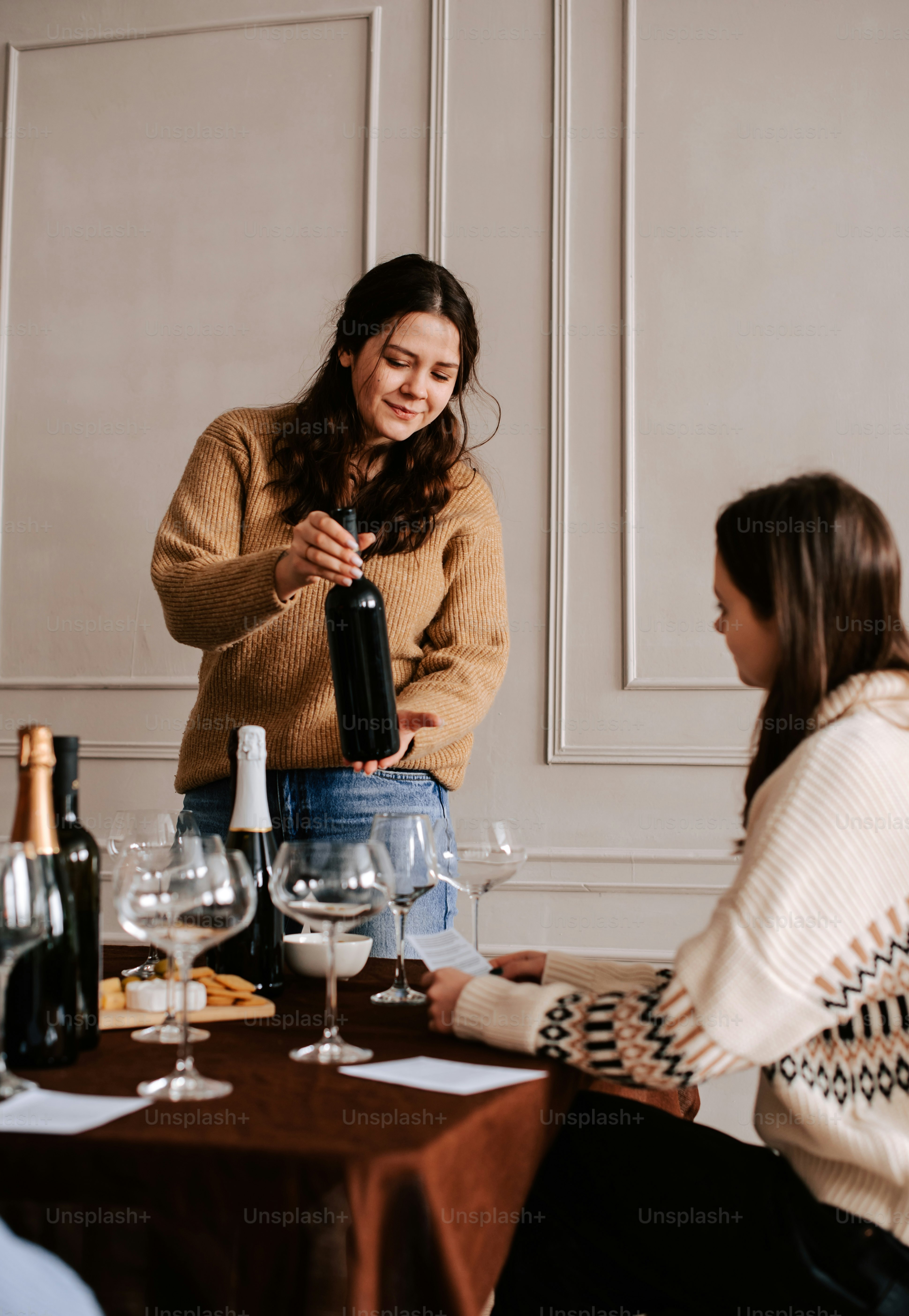 eine Frau, die mit einer Flasche Wein an einem Tisch steht