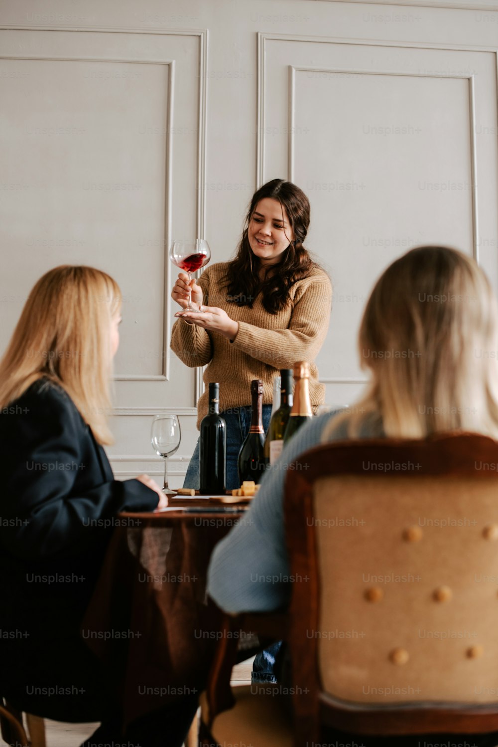 テーブルに�座りながらワインのグラスを持つ女性
