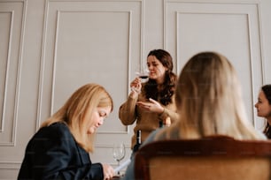 a group of women sitting around a table drinking wine