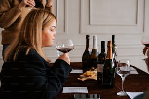 a woman sitting at a table with a glass of wine