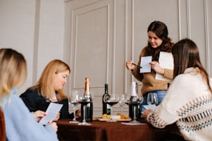 un gruppo di donne sedute intorno a un tavolo con vino