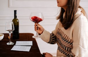 una mujer sentada a la mesa con una copa de vino