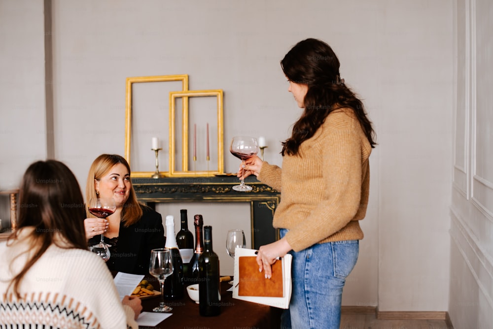 a group of women sitting around a table drinking wine