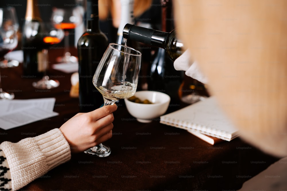 テーブルでグラスにワインを注ぐ人