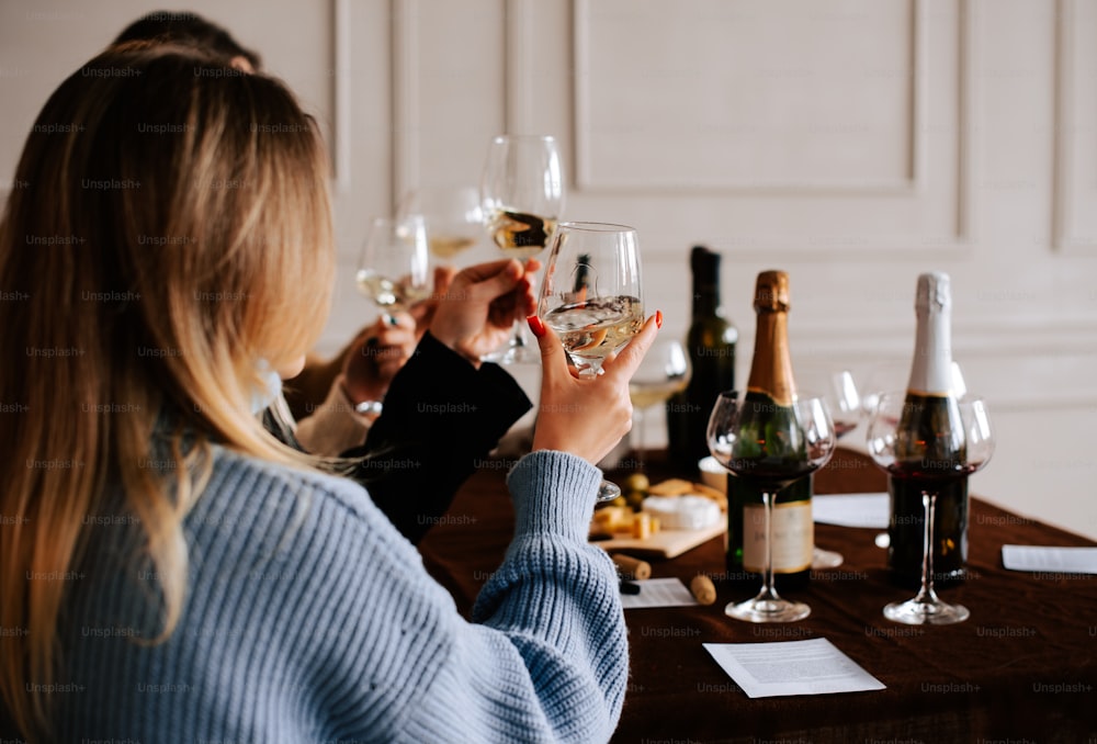 a woman sitting at a table holding a glass of wine