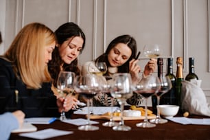 Tres mujeres sentadas en una mesa con copas de vino