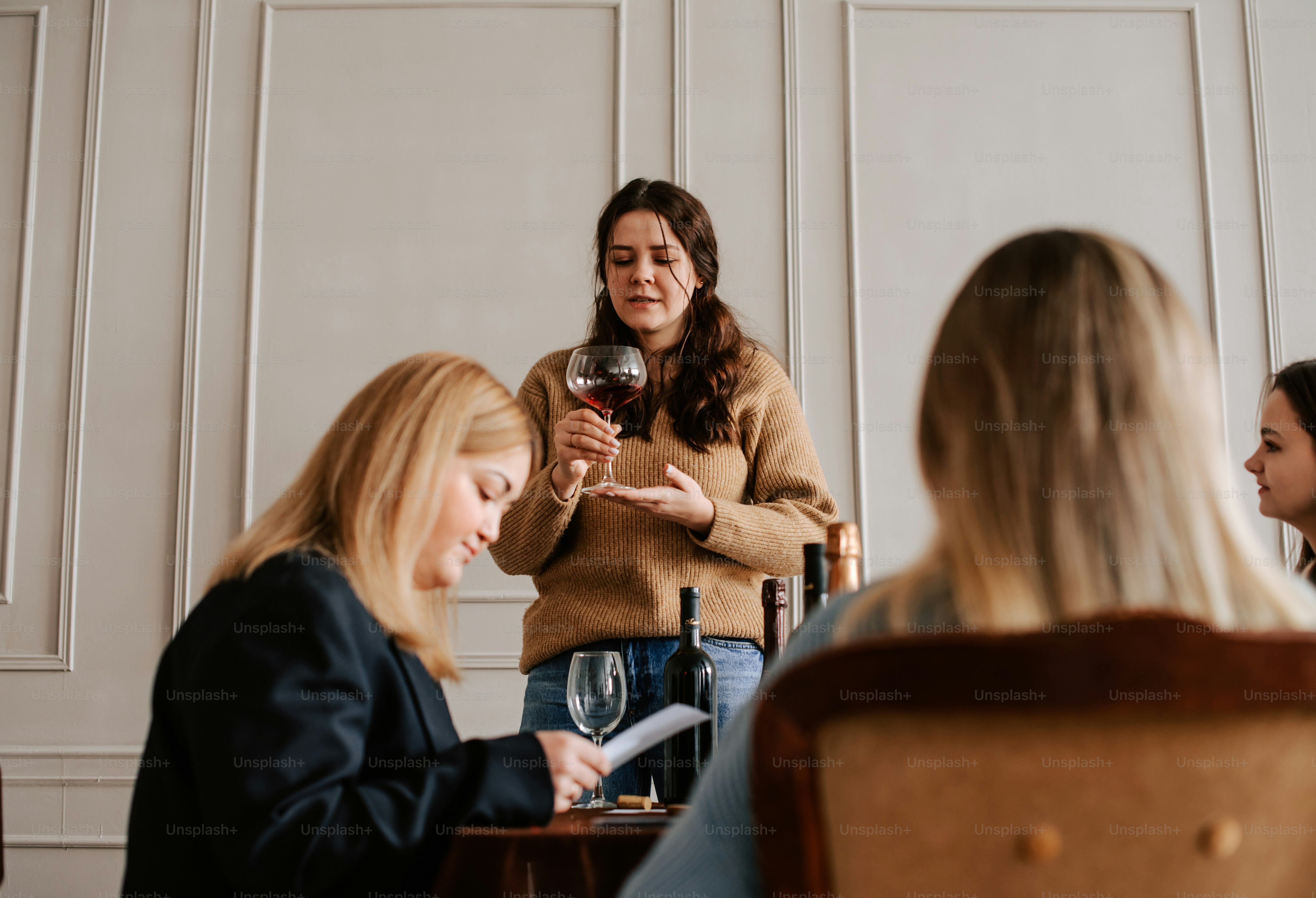 eine Gruppe von Frauen, die um einen Tisch sitzen und Wein trinken