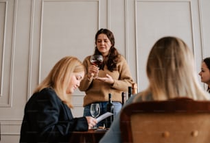 un grupo de mujeres sentadas alrededor de una mesa bebiendo vino