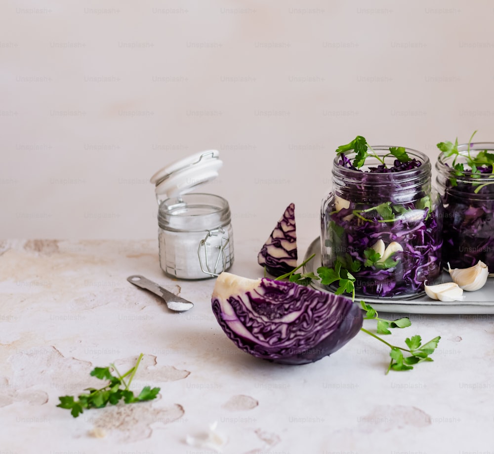 a plate topped with purple cabbage next to a jar of pickles
