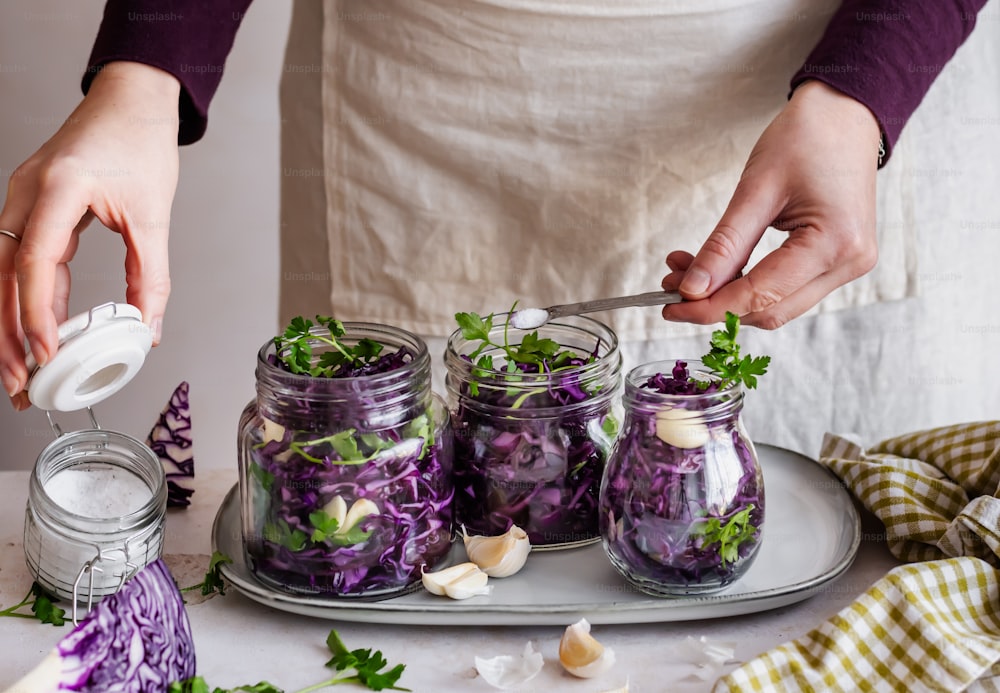 a person in a white apron is putting a jar of purple cabbage